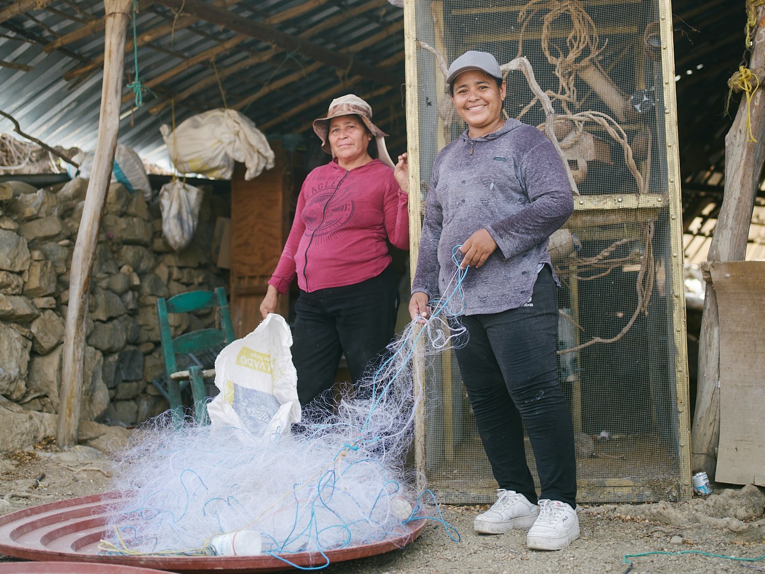Two women de-tangling their fishing nets.